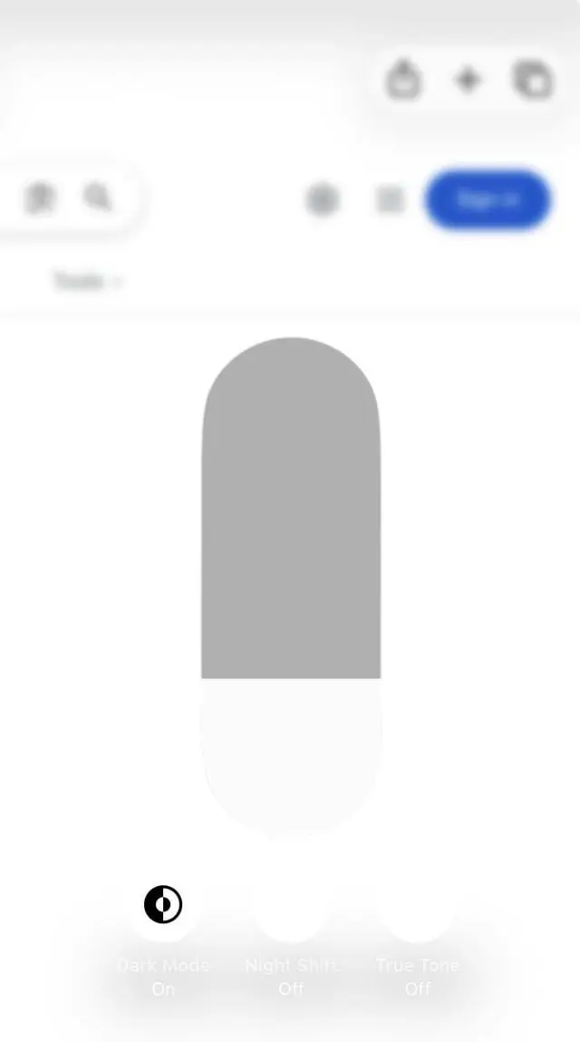 iOS 26 Screenshot featuring a translucent Liquid Glass overlay on a white background. Very poorly contrasting text can been seen below, ‘Dark Mode On’, ‘Night Shift Off’, and ‘True Tone Off’