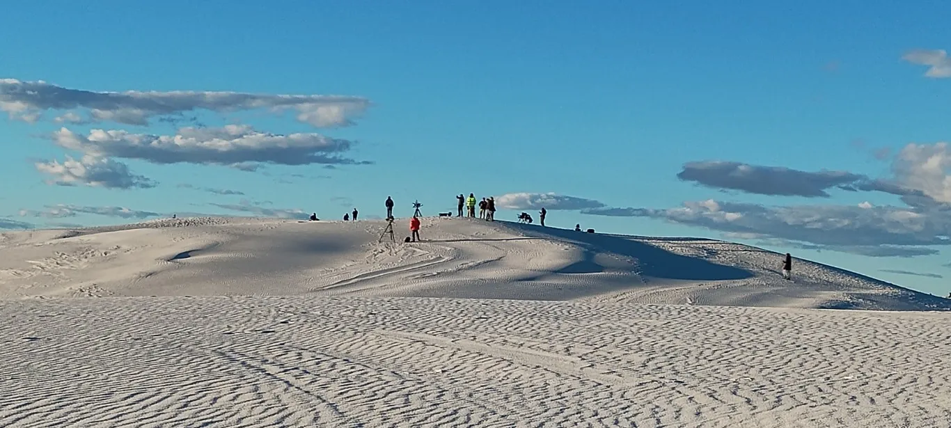 A movie crew set up on a white sand dune